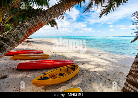 Des kayaks à belle plage tropicale avec palmiers, le sable blanc, l'eau de l'océan turquoise et bleu ciel à Îles Cook, Pacifique Sud Banque D'Images