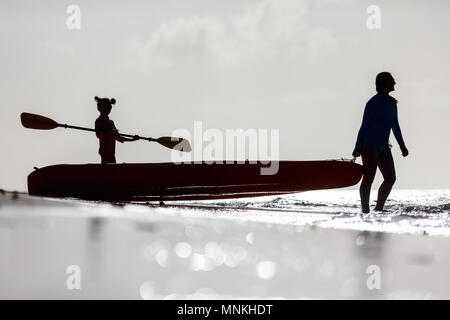 Silhouettes famille de mère et fille à la pagaie en kayak au coucher du soleil de l'océan tropical Banque D'Images