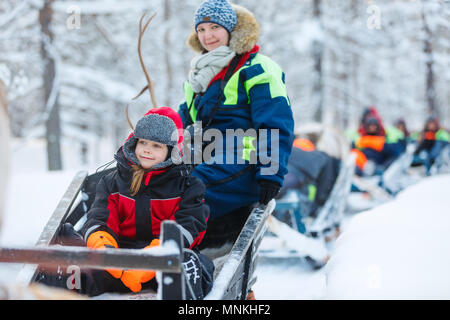 Mère de famille et petite fille à reindeer safari en forêt d'hiver en Laponie, Finlande Banque D'Images