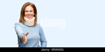 Femme blessée wearing neck brace collar détient mains accueillant dans le handshake pose, l'expression de la confiance et de la réussite, de l'accueil concept bleu isolé backgrou Banque D'Images