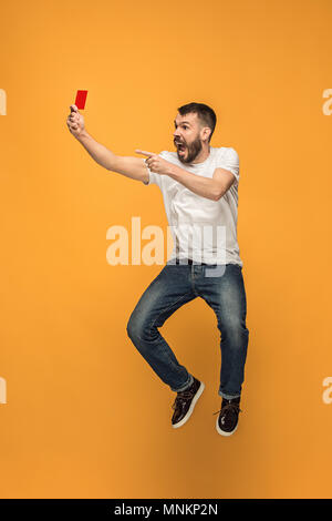 Supporter de football avec carte rouge sur fond orange Banque D'Images