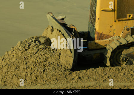 Close-up, flou, lame racleuse de bulldozer jaune en poussant le sable de la plage, la construction, le terrassement, motion, œuvres de la terre Banque D'Images