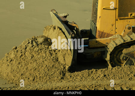 Close-up, détail, raclage bulldozer jaune sable humide, travaillant sur des projets de gestion des plages, flou Banque D'Images