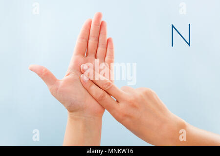 Alphabet d'épellation digitale. Femmes isolé sur fond bleu montrant sourd-muet BSL alphabet lettre N. Banque D'Images