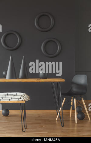 Des formes géométriques dans une chambre noire avec intérieur en bois d'une table, chaise et plancher en bois Banque D'Images