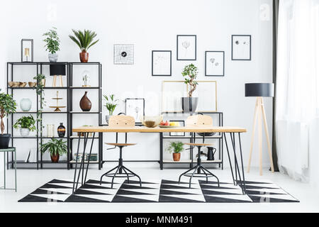 Chaise en bois à table sur tapis géométriques en scandi avec lampe d'intérieur de salle à manger Banque D'Images