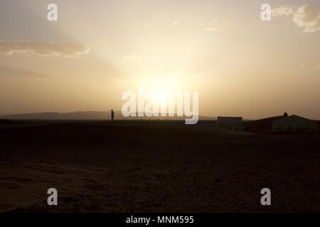 Une personne debout sur une dune de sable en regardant le coucher du soleil sur le désert de Zagora, Maroc Banque D'Images
