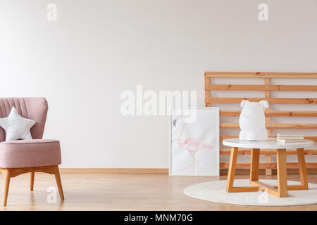 Lumière sur le banc de bois et d'affiches dans des chambre d'enfant avec chaise rose et l'oreiller contre le mur blanc Banque D'Images