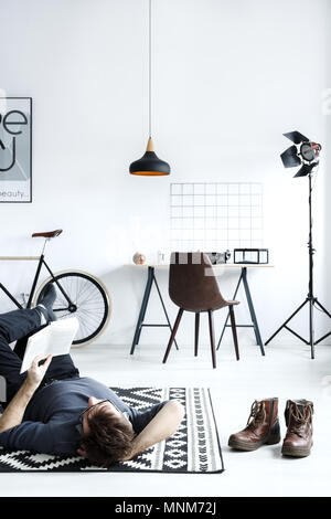 Homme étendu sur la moquette en blanc, cette chambre simple Banque D'Images