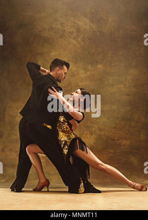 Salle de bal de danse en couple danse robe d'or sur fond de studio. Banque D'Images