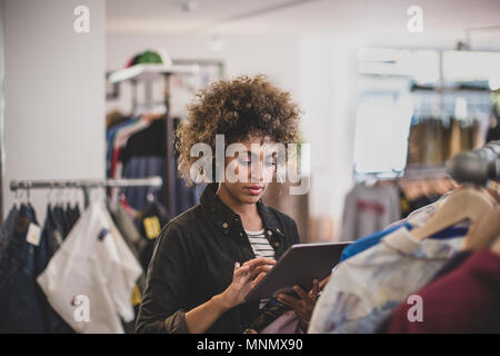 Store manager using digital tablet in a clothing store Banque D'Images