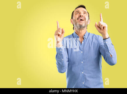 Beau moyen age homme heureux et surpris cheering pointant vers le haut Banque D'Images