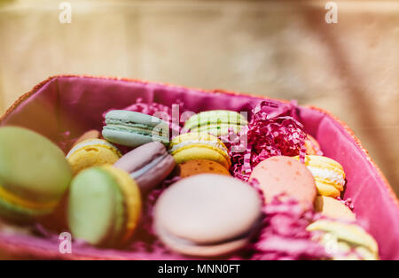 Macarons colorés et des fleurs sur les tables en bois. Macarons sucrés en boîte cadeau. Mise à plat Banque D'Images