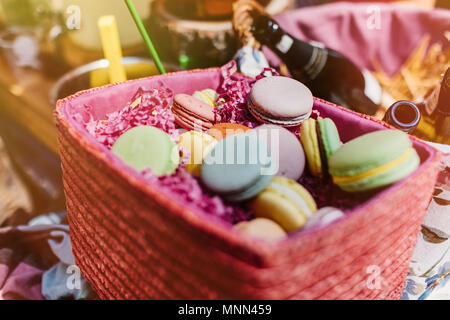 Macarons colorés et des fleurs sur les tables en bois. Macarons sucrés en boîte cadeau. Mise à plat Banque D'Images