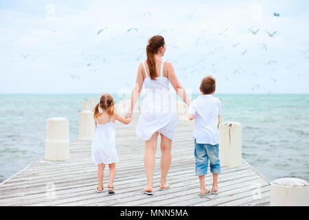Vue arrière de la mère et les enfants sur un quai en bois à marcher vers des centaines d'oiseaux de mer Banque D'Images