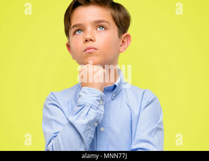 Beau Tout Petit Enfant Aux Yeux Verts Jusqu A La Pensee Et L Expression De Doute Et Me Demande Sur Fond Jaune Photo Stock Alamy