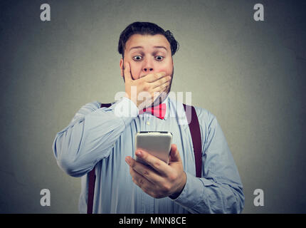 Young man looking at smartphone avec sentiment profond choqué et effrayé. Banque D'Images