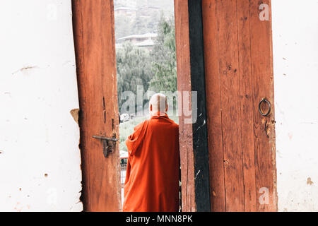 Un moine bouddhiste debout par une porte de Changangkha Lhakhang, Bhoutan Banque D'Images