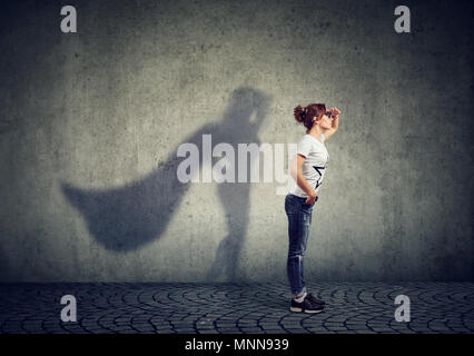 Vue latérale d'une femme d'imaginer d'être un super héros à la aspirait. Banque D'Images