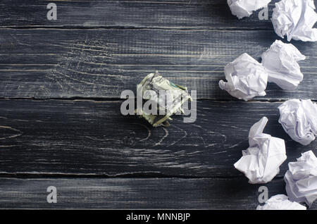 Un dollar froissé sur une table à côté des boules de papier blanc. Le processus de réflexion et de trouver de nouvelles idées d'affaires, des solutions rentables. De l'attraction en Banque D'Images