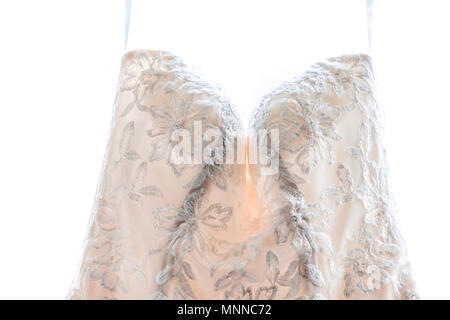 Gros plan du robe de mariage pendaison en face de la fenêtre, isolé sur fond blanc montrant les détails, la texture de matériel de dentelle, motif floral fleurs Banque D'Images