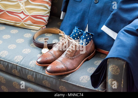 Nouveau cuir hommes chaussures brunes encore gros plan sur la vie de la table bleue avec chaussettes, regarder, costume pour se préparer un mariage ou préparation à l'entrevue dans la salle Banque D'Images