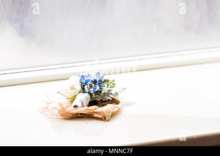 Une boutonnière fleur de mariage avec broche sur rebord de fenêtre de bas isolé avec ruban vert floral bleu au matin dans la pièce de l'hôtel Banque D'Images