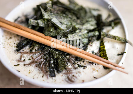 Gros plan macro de nouilles de sarrasin soba soupe japonaise avec des Algues Nori, le gingembre, la noix de coco verte sur le bouillon chaud, froid l'été, Baguettes en bambou Banque D'Images