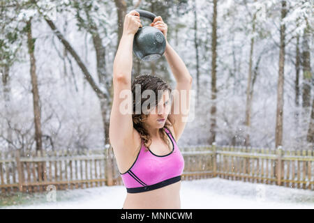 Jeune femme fit l'entraînement avec kettlebell livre 45 dans l'extérieur l'extérieur du parc holding le levage de poids pendant l'hiver la neige Banque D'Images