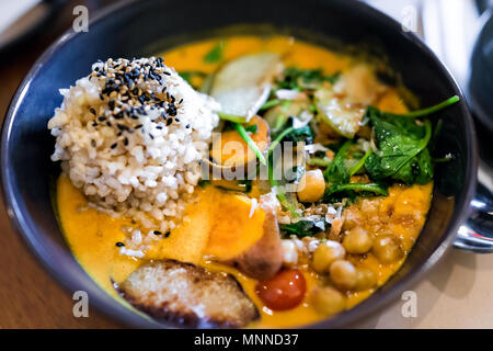 Gros plan du repas indien le déjeuner ou le dîner dans le restaurant asiatique plat traditionnel ou un café avec légumes patate douce orange curry, riz brun, vert cilant Banque D'Images