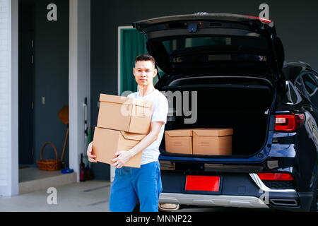 Mature Asian man carrying cardboard boxes de coffre de voiture à new home Banque D'Images