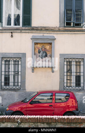 Une petite voiture rouge en face d'un vieux bâtiment à Lucca, Italie. Banque D'Images