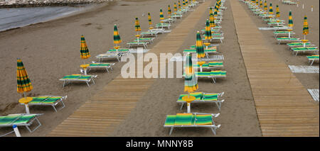 Plein de plage avec transats parasols fermés tous les deux par la mer vide Banque D'Images
