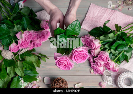 Un fleuriste au travail. Femme élégante mains recueillir un mariage bouquet de roses roses. Les gens dans le processus de travail Banque D'Images