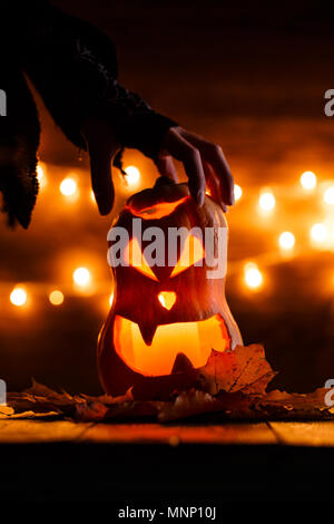 Photo de halloween citrouille coupées en forme de visage avec la main de la sorcière Banque D'Images