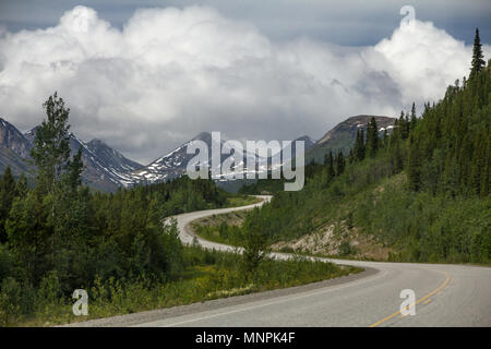 Tronçon de route de l'Alaska sinueuse vers l'ouest de Watson Lake. BC à Whitehorse, au Yukon, les courbes gracieusement à travers les collines boisées et les montagnes enneigées Banque D'Images