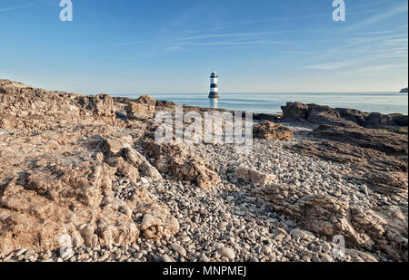 Penmon Point Lighthouse et érodé shore cliff à bright matin ensoleillé. L'île d'Anglesey dans le Nord du Pays de Galles, Royaume-Uni Banque D'Images