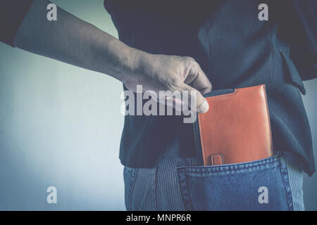 Close-up of a la main de voleur de voler le porte-monnaie pour une femme. Voleur voler wallet de poche arrière, d'une femme. Banque D'Images