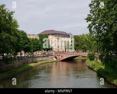 Les gens traversant un vieux pont au-dessus de la rivière Ill, Strasbourg, France. Banque D'Images