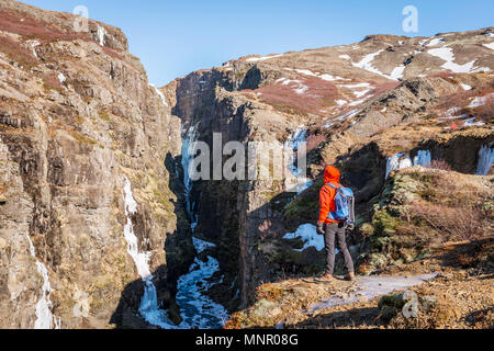 Dans l'homme debout à la veste orange de canyon Cascade b Carmen, Hvalfjarðarsveit, Vesturland, Islande Banque D'Images