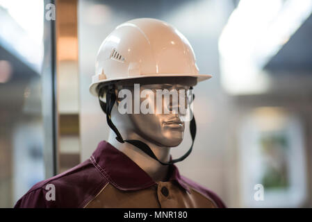 Man : des vêtements en bleu de travail et casque jaune isolé sur fond blanc. Banque D'Images