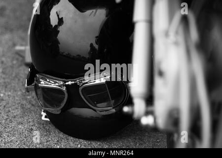 Moto vintage Casque avec lunettes portant sur le sol à côté d'un scooter Banque D'Images