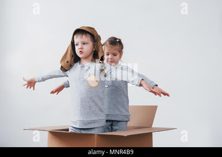 La petite enfance ludique. Petit garçon s'amuser grâce à la boîte de carton. Garçon prétendant être pilote. Little Boy and girl having fun at home Banque D'Images