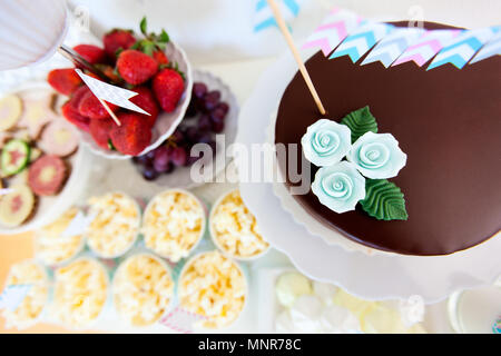 Les petits fruits, du maïs soufflé, des canapés, des bonbons et un gâteau au chocolat sur une table de dessert at party Banque D'Images