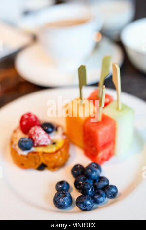 Délicieux petit déjeuner avec des fruits tropicaux, des petits fruits, mini-tart et tasse de café chaud Banque D'Images