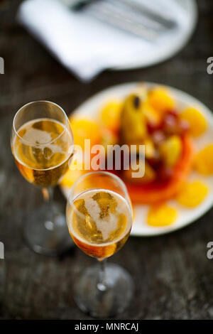 Deux verres avec du champagne et des fruits sur le plateau en bois vintage servi pour une occasion spéciale ou une fête Banque D'Images