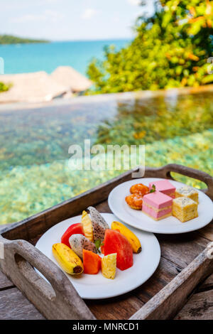 Service en chambre de délicieux fruits et desserts servis sur une table proche piscine Banque D'Images