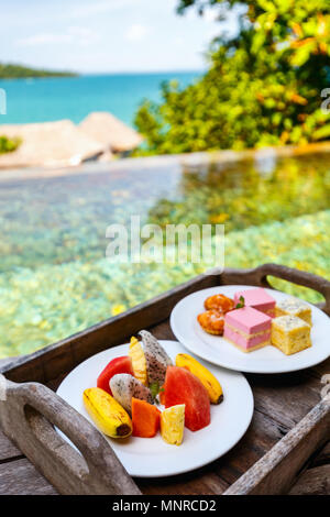Service en chambre délicieux déjeuner des hamburgers, des fruits et des bonbons servis sur une table proche piscine Banque D'Images