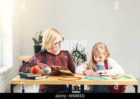 Style anglais enseignant porte lunettes étudie avec kid school girl, table avec des livres et des lettres, de la langue d'apprentissage des enfants en classe élégant blanc processus Banque D'Images