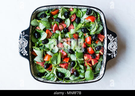 Le pourpier salade avec tomates et olives noires en Bol en porcelaine. L'alimentation biologique. Banque D'Images